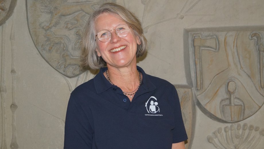 Vera Götz, eine Frau mit kinnlangen, grauen Haaren und Brille, lächelt in die Kamera. 