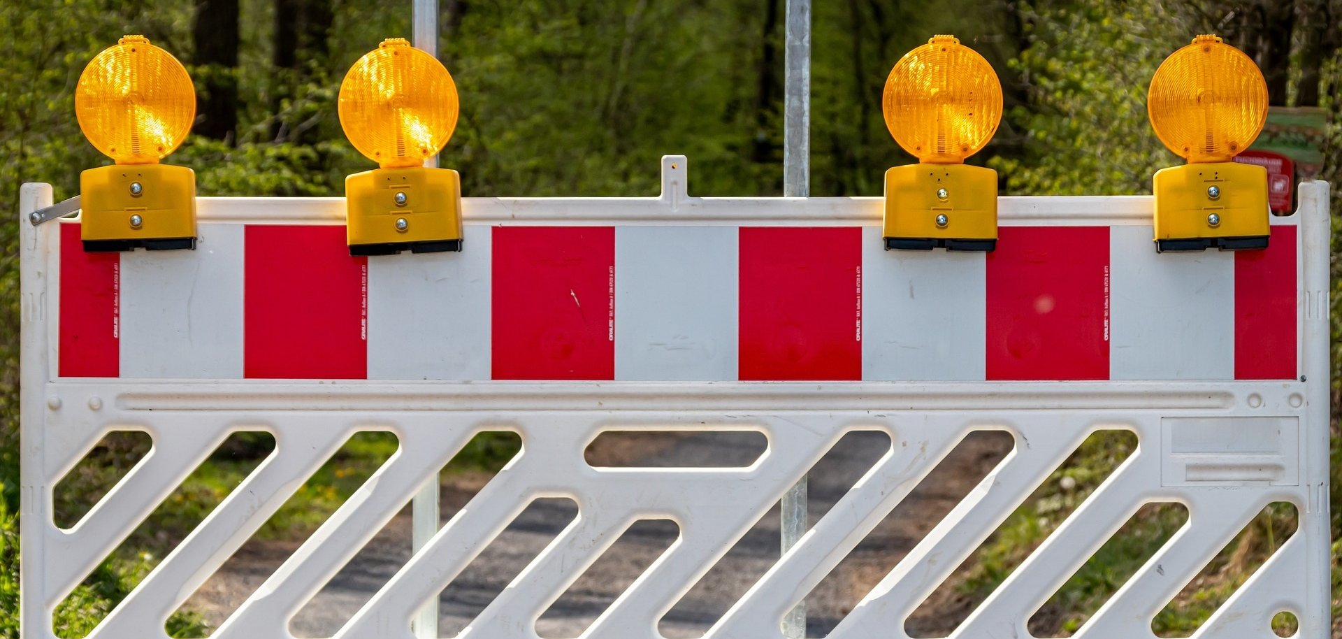 Eine Baustellenabsperrung vor grünem Hintergrund. 