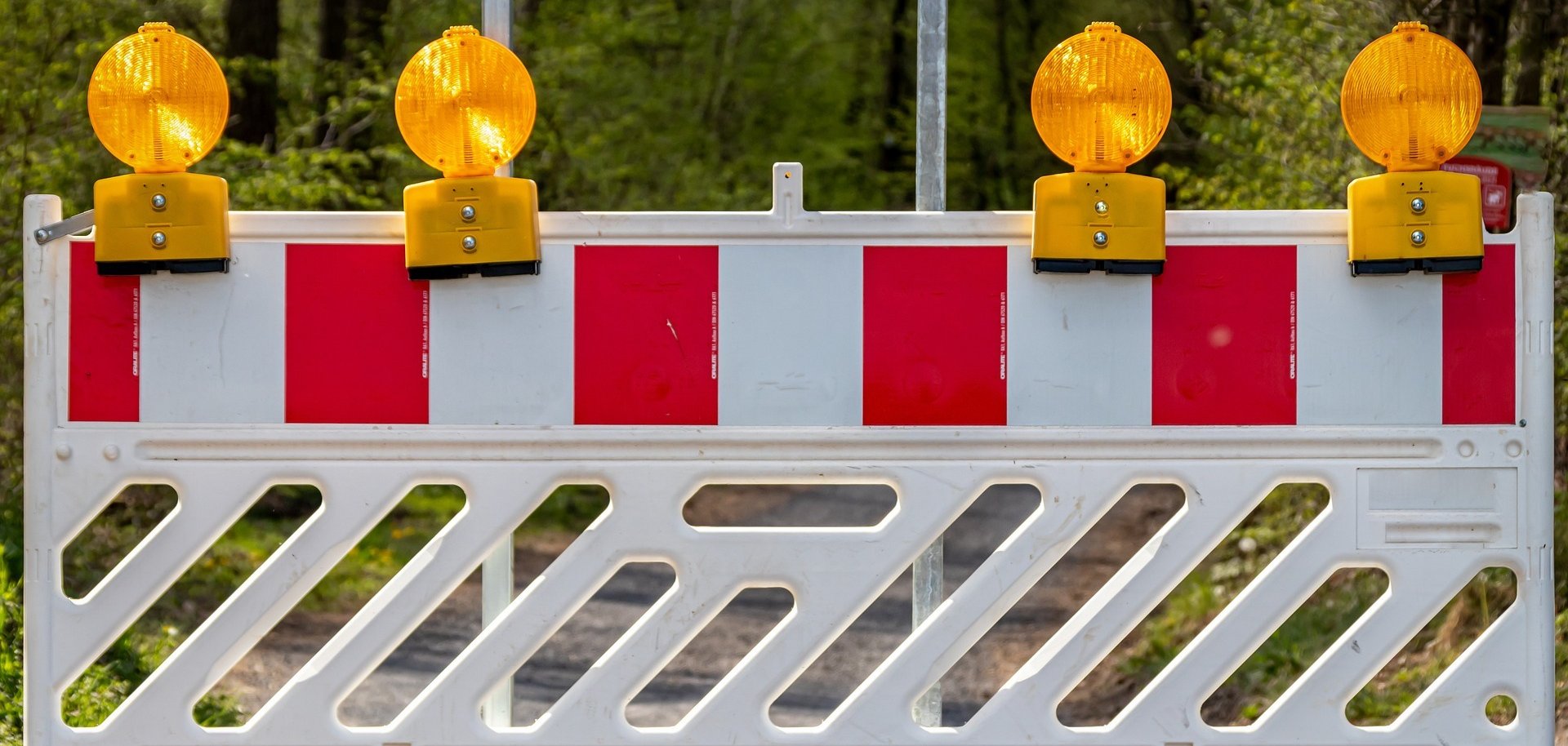 Eine Baustellenabsperrung vor grünem Hintergrund. 