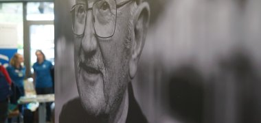 Ein großformatiges Foto, im Hintergrund sind Menschen zu sehen.