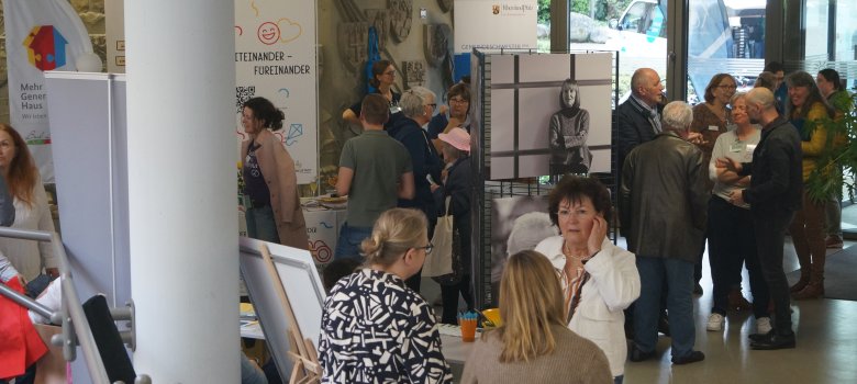 Menschen stehen an Infoständen und sprechen in Gruppen miteinander.