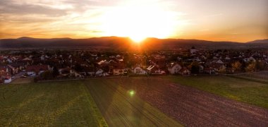 Das Dorf Niederkirchen, beleuchtet von der hinterm Haardtrand hervorblitzenden Sonne. 