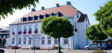 Das Sturmfeder'sche Schloss in Dirmstein, ein großes, weißes Herrenhaus mit Gibeln im Dach. 