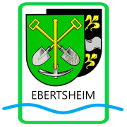 Das Wappen von Ebertsheim - Grün, darauf gekreuzt zwei Schaufeln und eine Spitzhacke - im Vordergrund. Dahinter fast verdeckt das schwarze Wappen von Rodenbach, sichtbar sind zwei gelbe Lilien und ein Stück vom quer teilenden Wellenbalken. Unter den Wappen der Schriftzug Ebertsheim und eine blaue Wellenlinie.