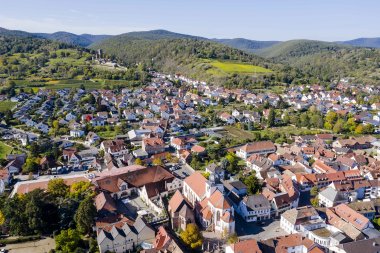 Luftaufnahme von Wachenheim, im Hintergrund die Wachtenburg und bewaldete Hügel. 
